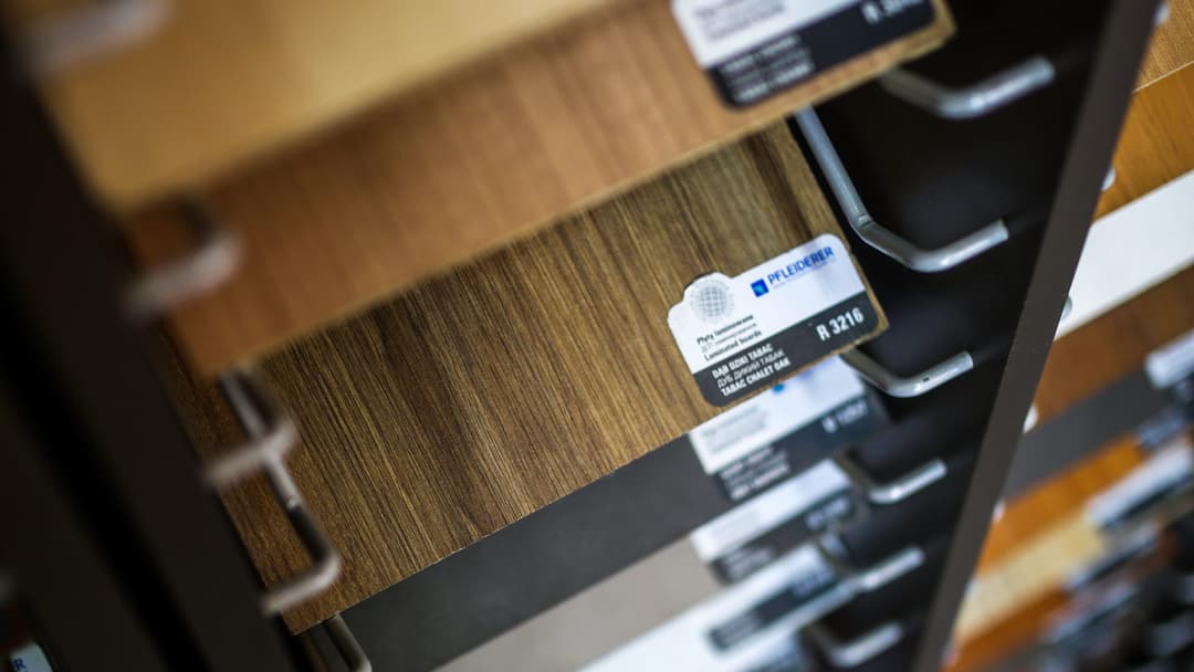 Laminated board samples on a display stand with manufacturer labels and decor codes