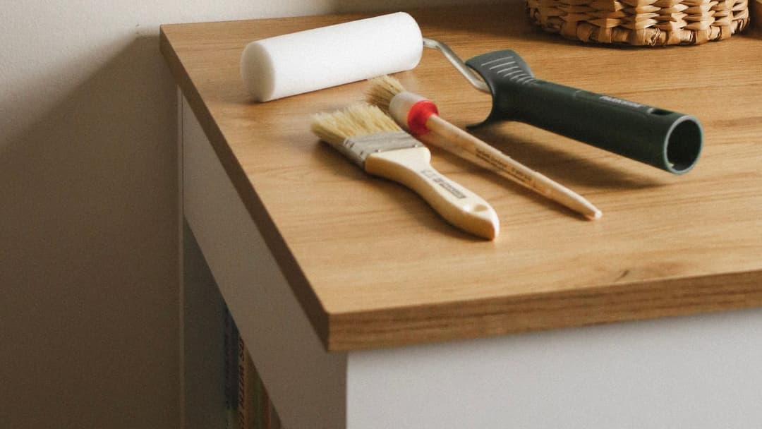 Roller and brushes on an oak-decor worktop of a white cabinet