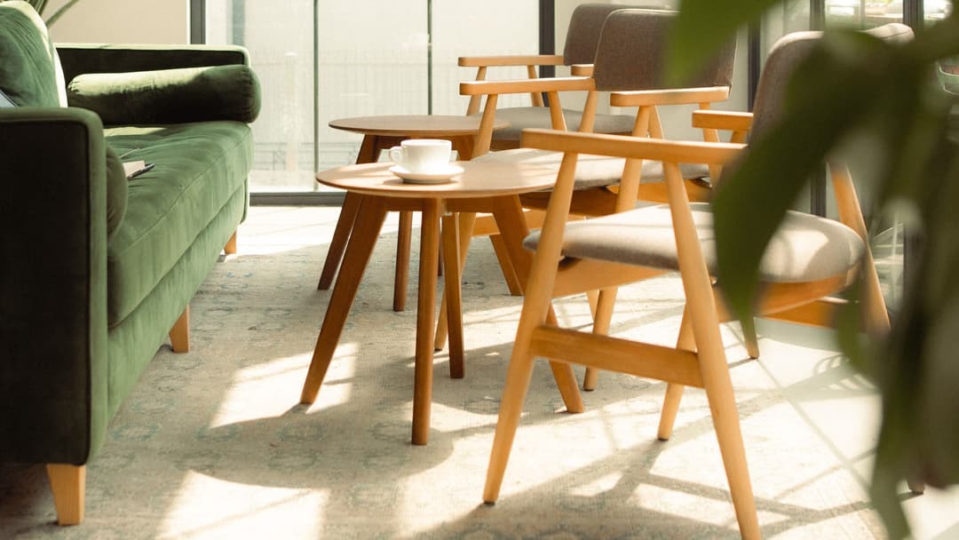 Bright interior with wooden chairs, round side tables and a green sofa